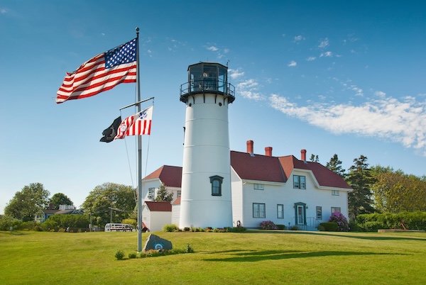 Weißer Leuchtturm mit Wärterhaus und amerikanischer Flagge auf Cape Cod