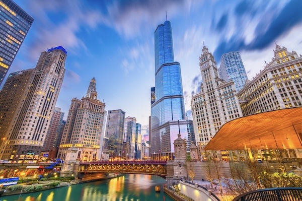Hochhäuser von Chicago zu beiden Seiten des Flusses, im Vordergrund eine Brücke, in der Abenddämmerung
