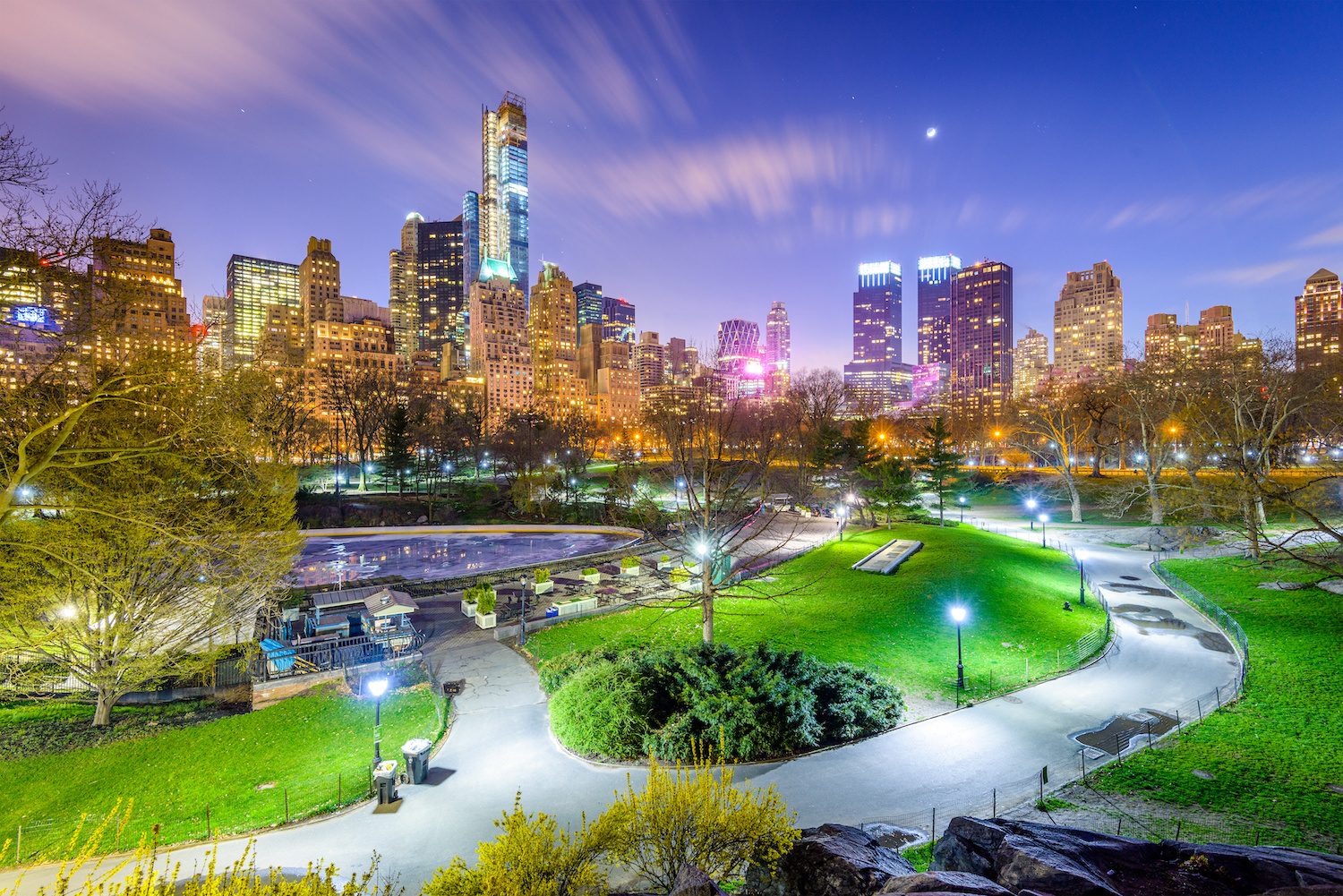 Central Park am Abend, dahinter die beleuchtete Skyline von New York