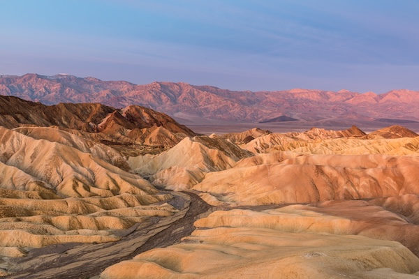 Erodierte Badlands im Death Valley vor einer Bergkette