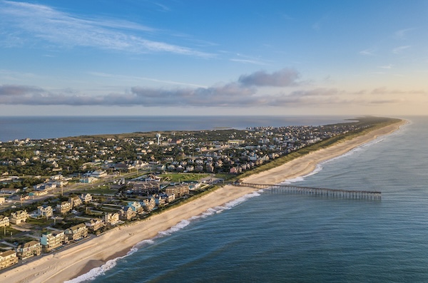 Luftbild der Outer Banks mit langem Sandstrand, Strandhäusern und einem Pier