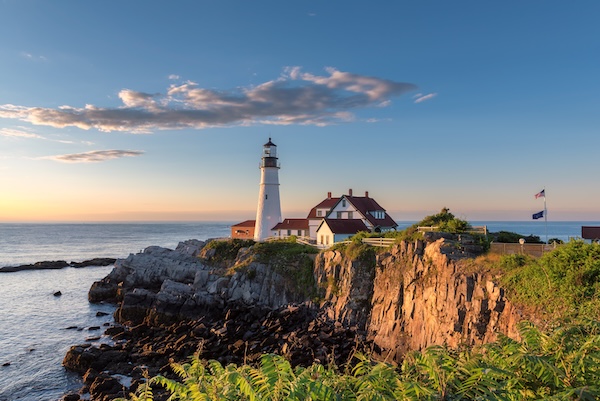 Leuchtturm mit rot gedecktem Wärterhaus auf einer Felsklippe am Meer bei Portland