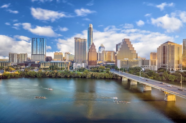 Die Skyline von Austin über dem Fluss, davor eine Brücke und Ruderboote