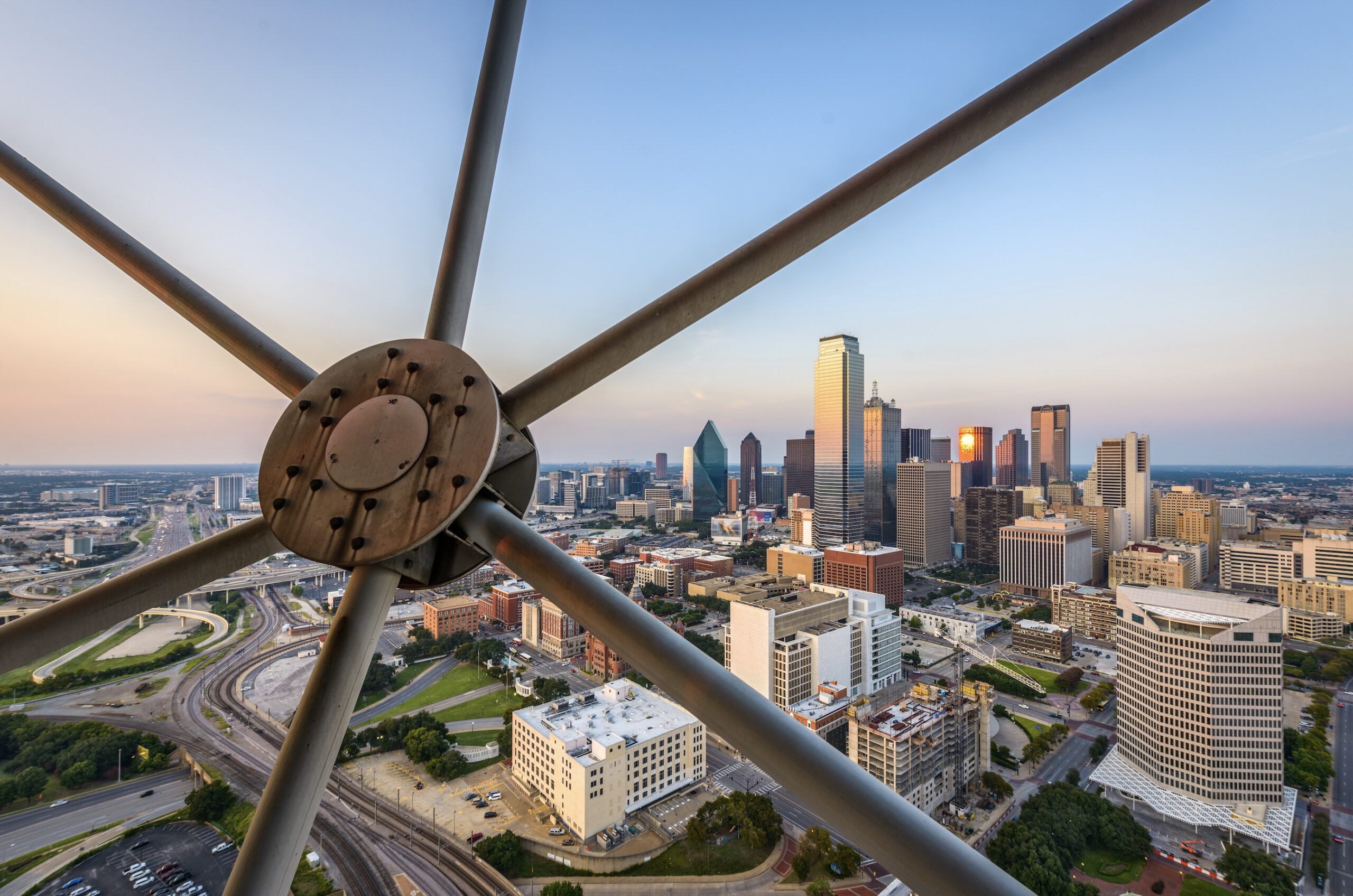 Blick zwischen den Streben eines Aussichtsturms auf die Skyline von Dallas bei Sonnenuntergang