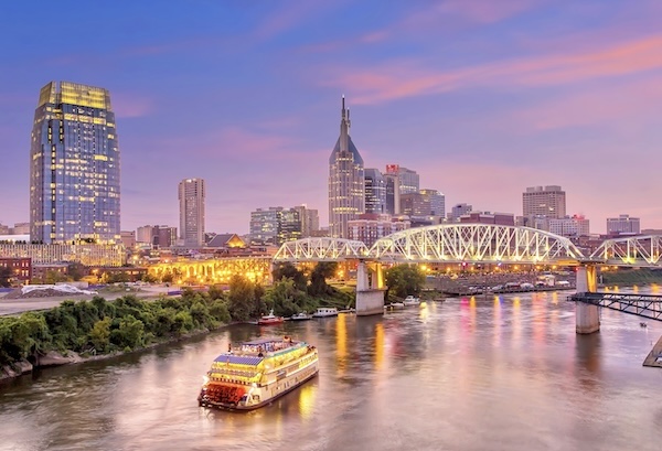 Die Skyline von Nashville in der Dämmerung mit Fachwerkbrücke und einem Schaufelraddampfer auf dem Fluss